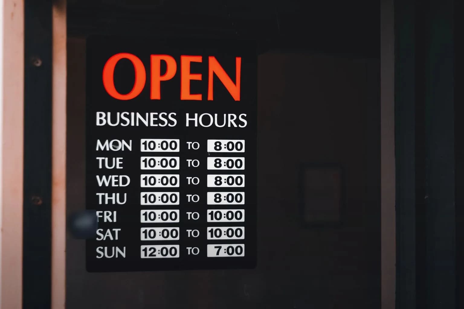 店门上挂着的营业中标牌和每周营业时间表