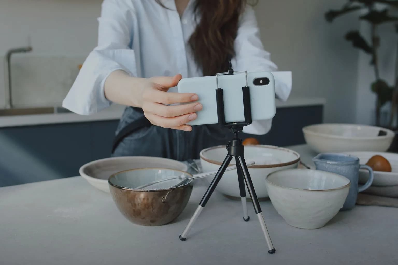 A phone on a small tripod set up to film bowls on a kitchen counter