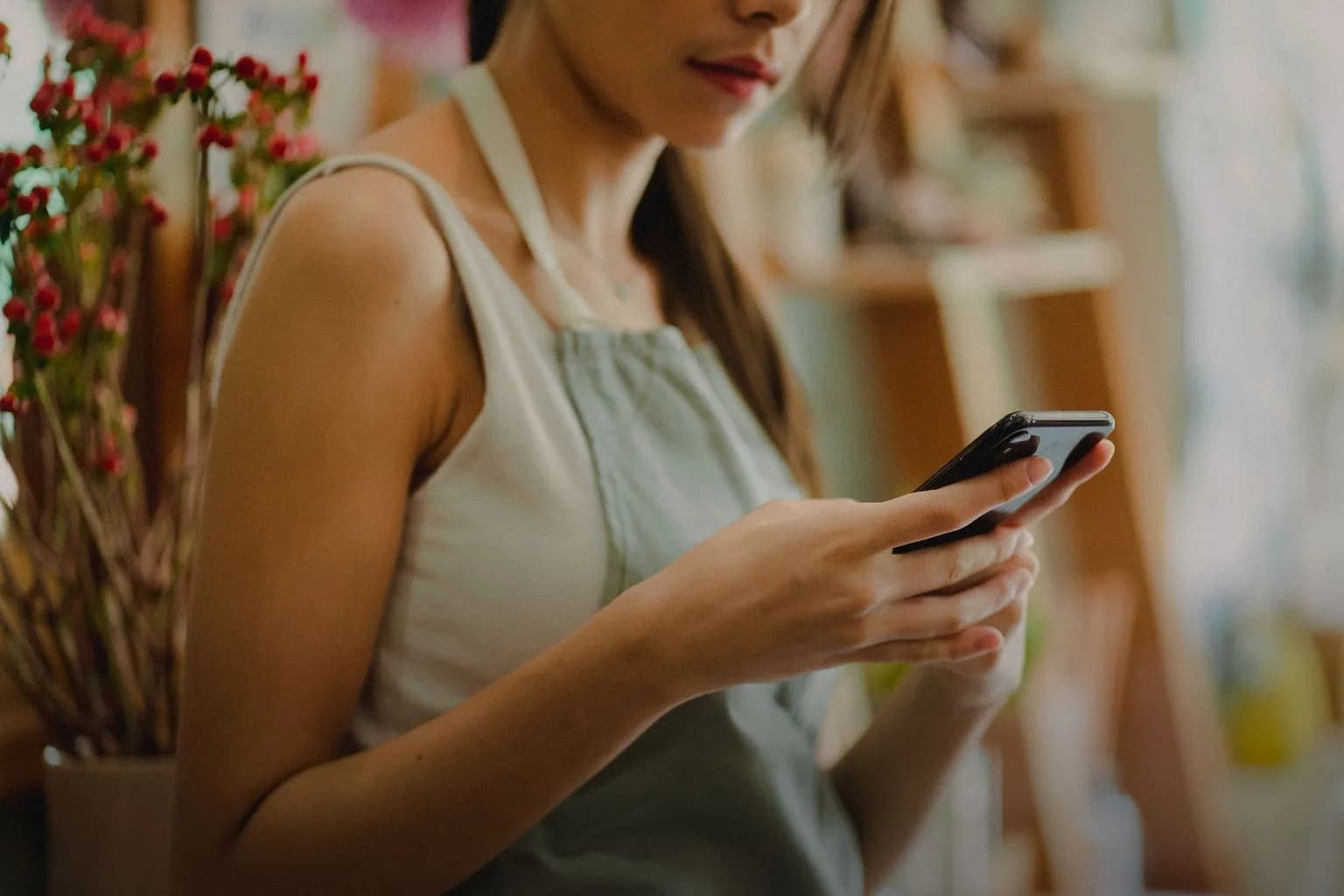 A florist in an apron looking at her phone